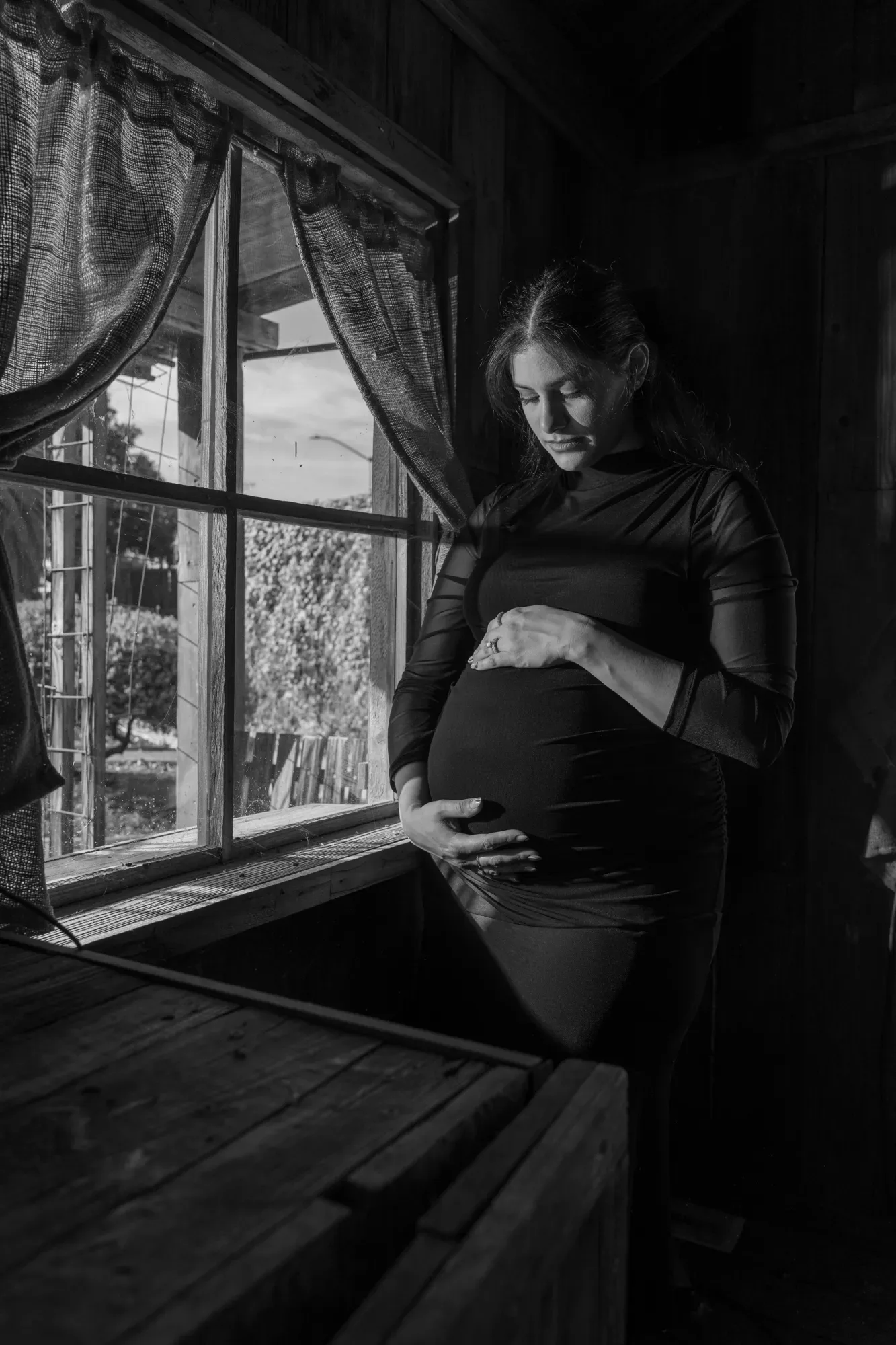 Black-and-white maternity portrait by a window