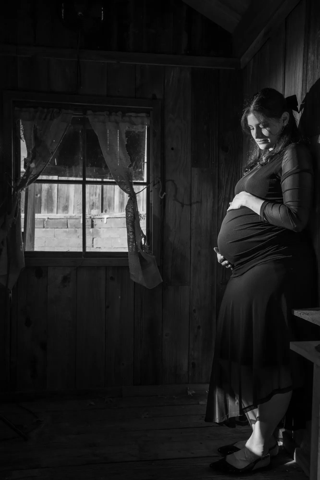Black-and-white maternity photo in a rustic cabin