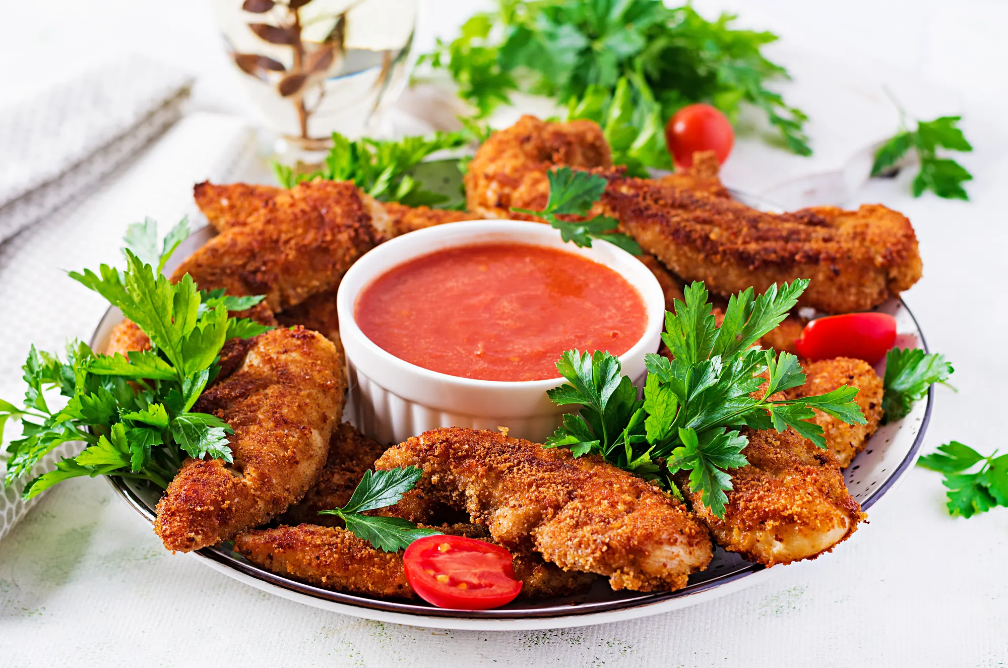 Crispy chicken tenders with dipping sauce and parsley