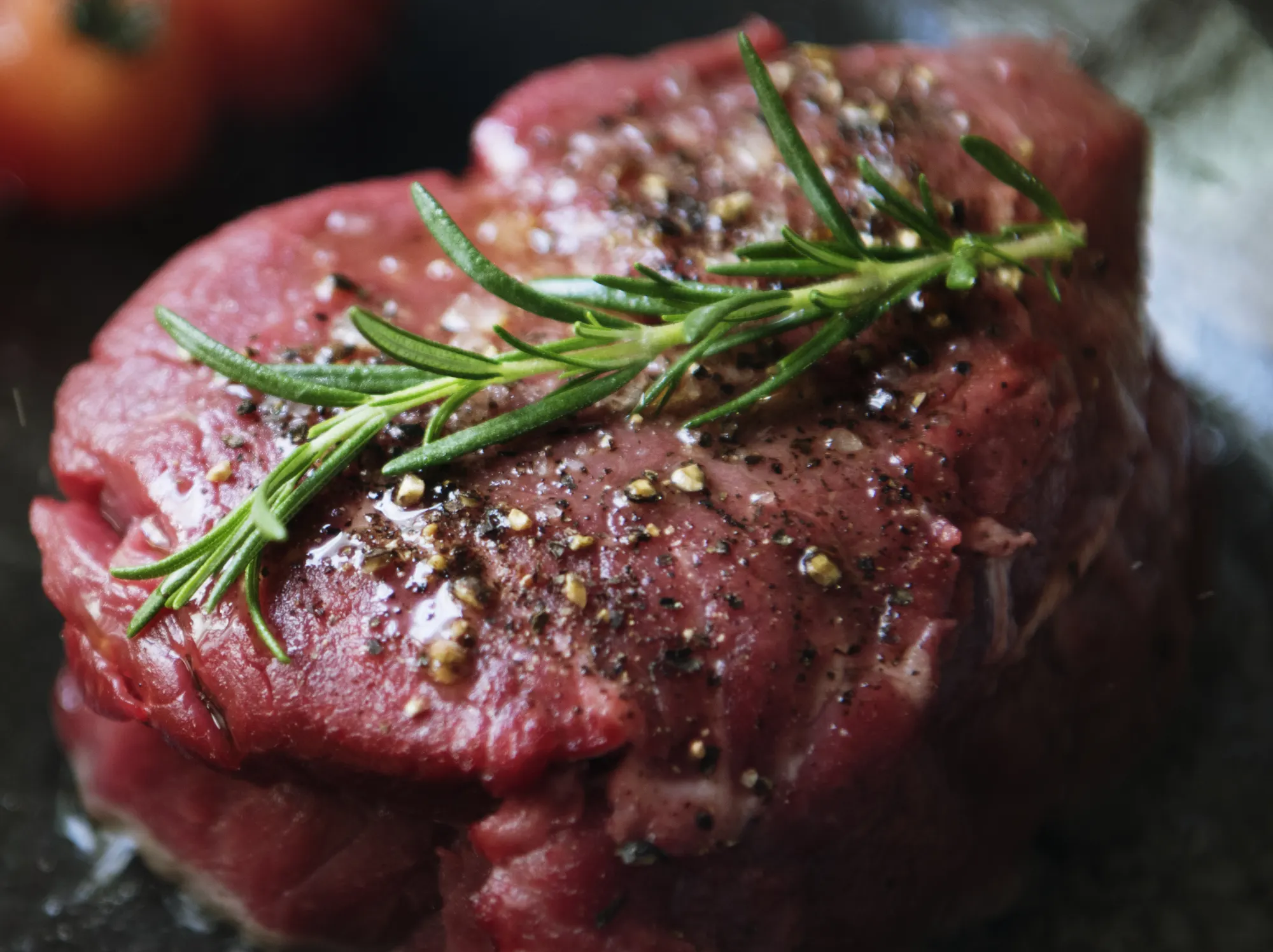 Raw steak seasoned with rosemary and pepper, close-up
