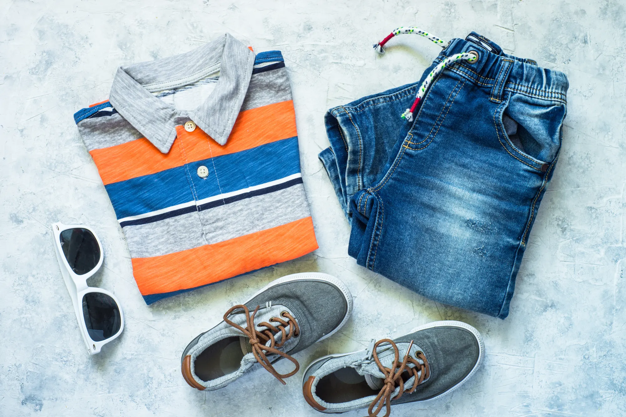 Kids' clothing flat lay with polo, jeans, sneakers and sunglasses, e-commerce photo